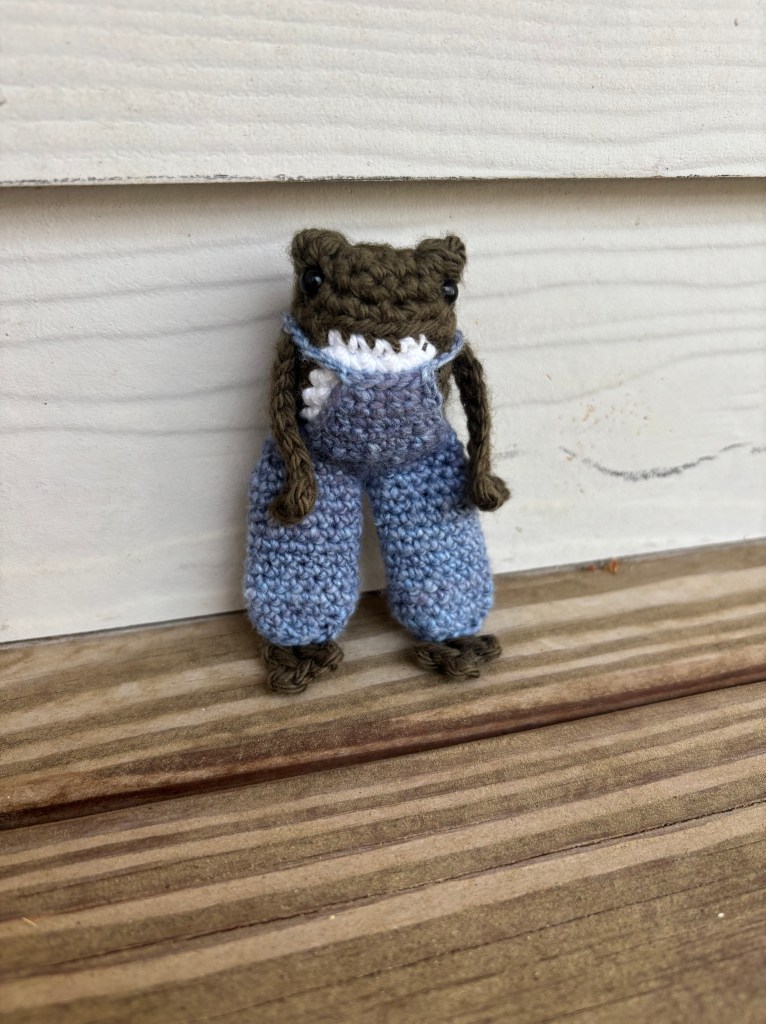 dark green crochet frog in overalls plushie